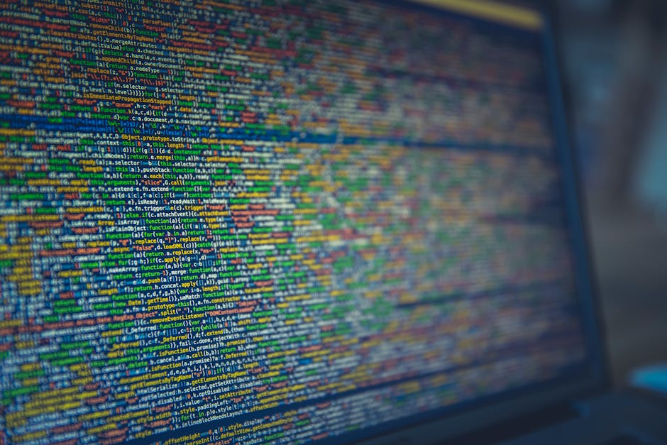A close-up of a computer screen displaying a dense, colorful array of programming code in various shades of blue, green, yellow, orange, and red. The code appears to consist of numerous lines of text